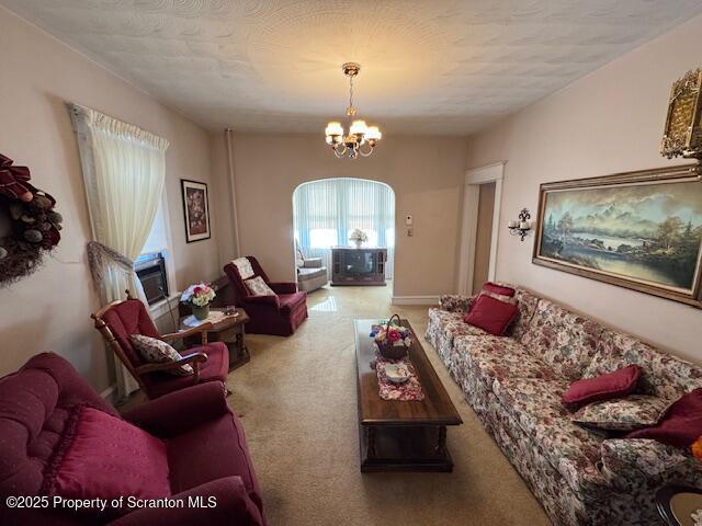 living room featuring an inviting chandelier, carpet floors, and a textured ceiling