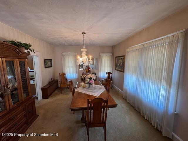 dining space featuring carpet and a notable chandelier