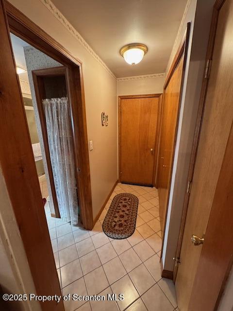 hall featuring crown molding and light tile patterned floors