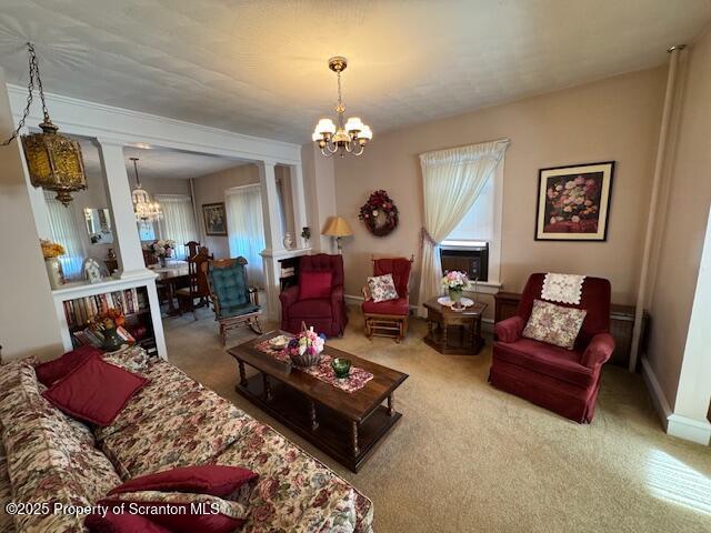 living room featuring an inviting chandelier, carpet floors, and ornate columns