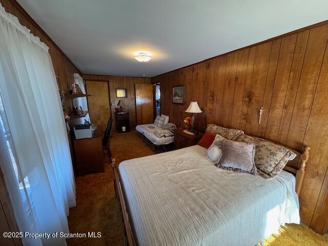 bedroom featuring wood walls and dark colored carpet