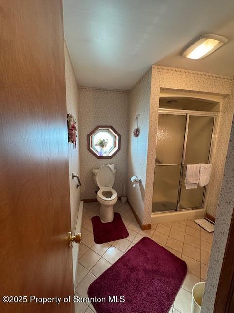 bathroom featuring tile patterned flooring, toilet, and walk in shower