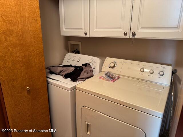 clothes washing area with cabinets and washer and dryer