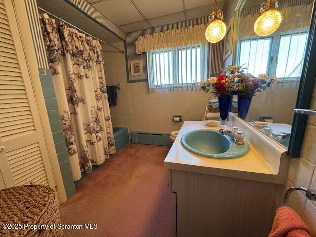 bathroom with a drop ceiling, a baseboard heating unit, vanity, and shower / bath combo with shower curtain