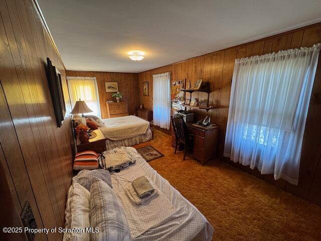 bedroom featuring carpet flooring and wood walls