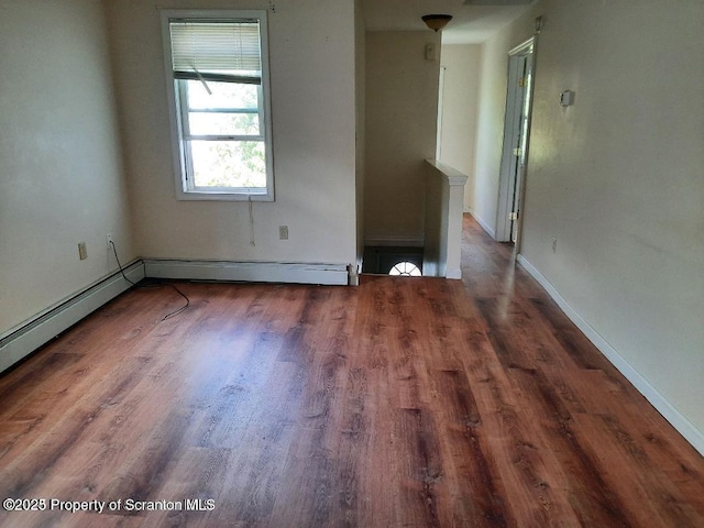 spare room featuring a baseboard heating unit and dark hardwood / wood-style floors