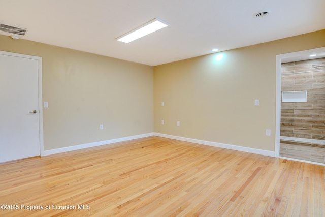 empty room with visible vents, light wood-style flooring, and baseboards