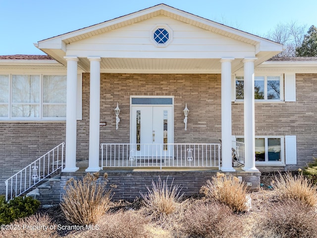 property entrance with brick siding and covered porch