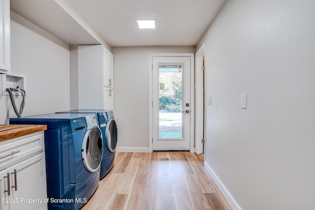 laundry room featuring separate washer and dryer, cabinet space, light wood-type flooring, and baseboards