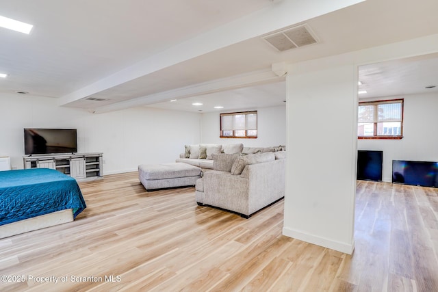 living area with wood finished floors, visible vents, and baseboards