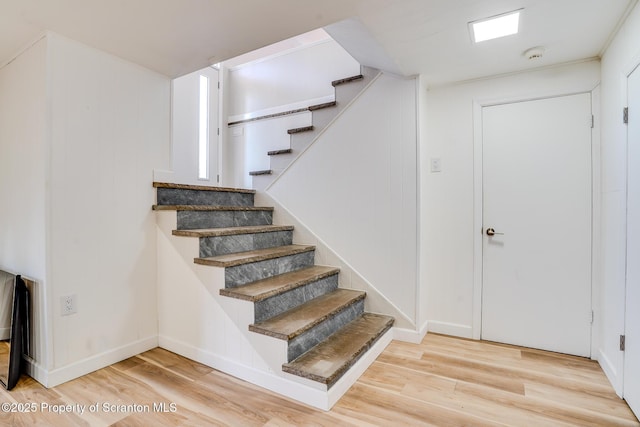 staircase with baseboards and wood finished floors