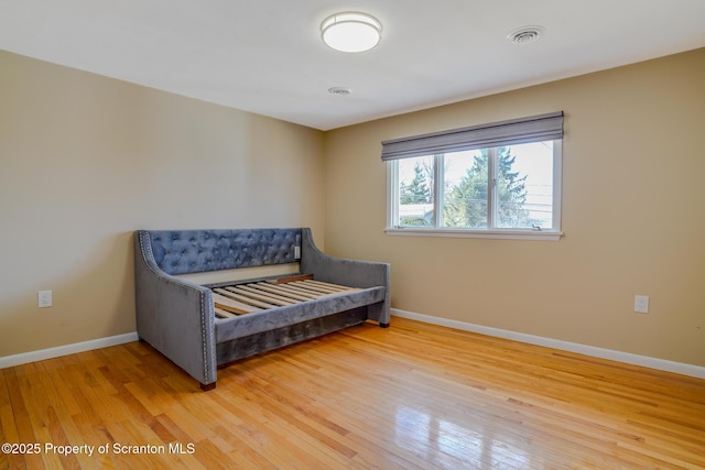 living area with light wood-style floors, visible vents, and baseboards