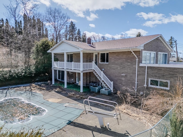 rear view of house featuring a chimney, stairs, central air condition unit, a patio area, and brick siding