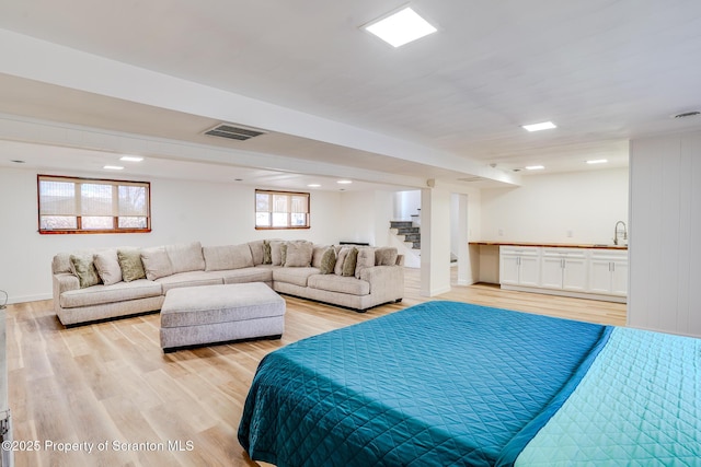 bedroom with light wood-type flooring, visible vents, and a sink