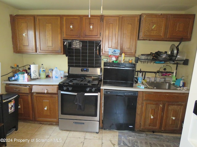 kitchen featuring stainless steel gas stove, light tile patterned flooring, sink, and black dishwasher