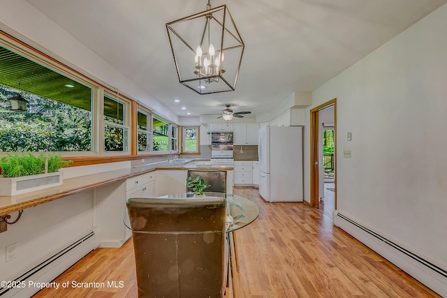 kitchen featuring light wood-style floors, freestanding refrigerator, a baseboard heating unit, and white cabinets