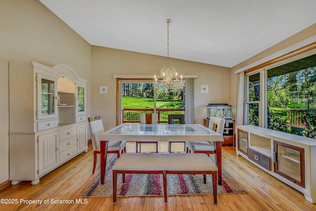 dining room with vaulted ceiling, light wood-style flooring, and a notable chandelier