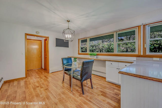 dining area with light wood-style floors, a baseboard radiator, and a chandelier