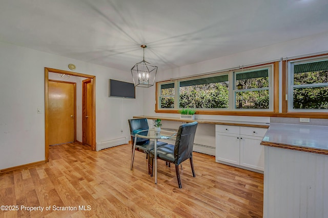 dining space with light wood-style floors, baseboards, a baseboard heating unit, and a notable chandelier