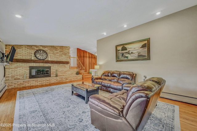 living area with baseboard heating, a fireplace, wood finished floors, stairway, and recessed lighting