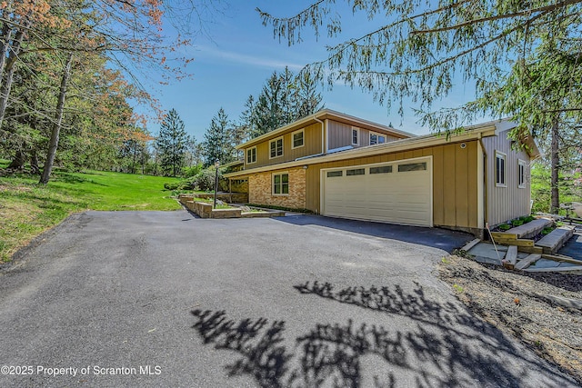 view of property exterior featuring a lawn, brick siding, aphalt driveway, and a garage
