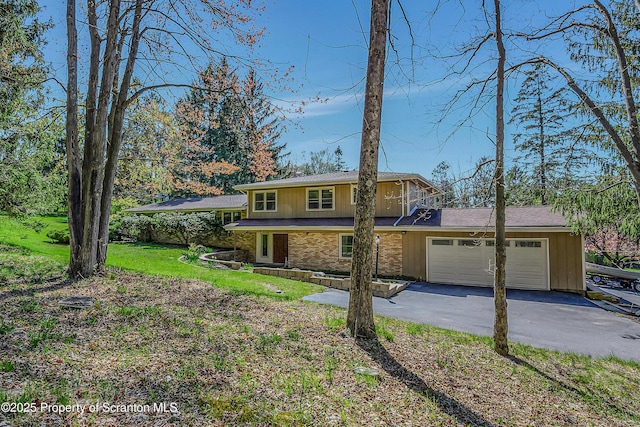 traditional-style house with brick siding, a garage, a front lawn, and aphalt driveway