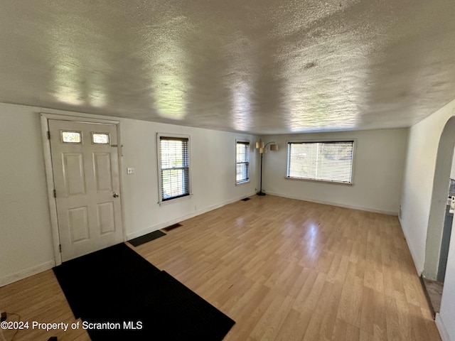 foyer entrance with a textured ceiling and light hardwood / wood-style floors