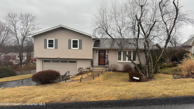 tri-level home with a garage, brick siding, and a front yard