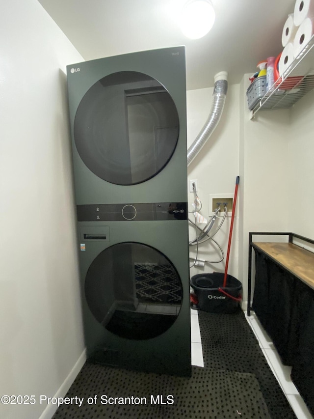 clothes washing area featuring laundry area, stacked washer and clothes dryer, and baseboards