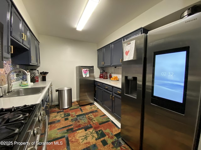 kitchen featuring a sink, baseboards, light countertops, appliances with stainless steel finishes, and decorative backsplash