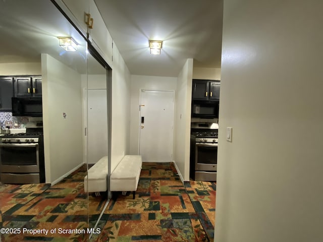 kitchen featuring stainless steel gas range, black microwave, backsplash, and dark cabinets