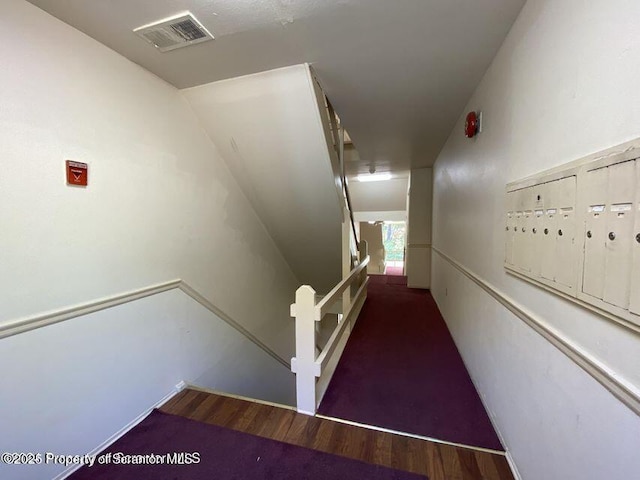 stairway featuring mail area, wood finished floors, and visible vents