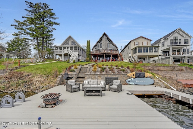 view of dock featuring a deck and an outdoor living space with a fire pit