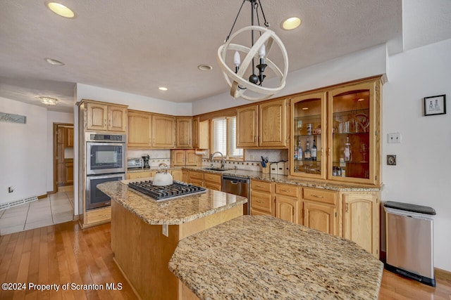 kitchen featuring tasteful backsplash, stainless steel appliances, sink, a kitchen island, and hanging light fixtures