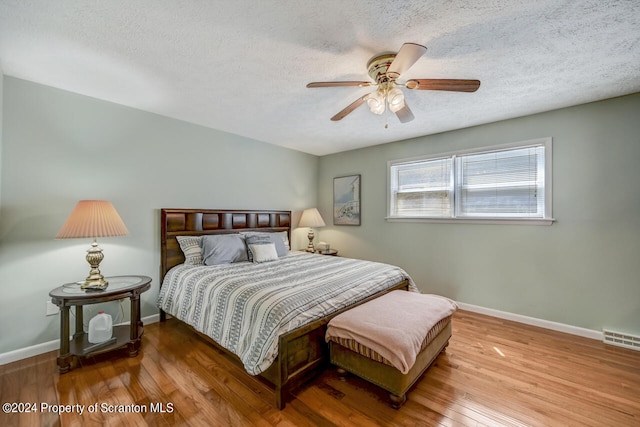 bedroom featuring hardwood / wood-style floors, a textured ceiling, and ceiling fan