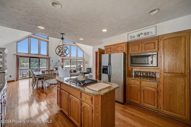 kitchen with a center island, an inviting chandelier, decorative light fixtures, light hardwood / wood-style floors, and stainless steel appliances