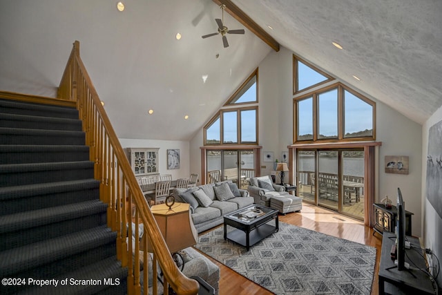 living room with beamed ceiling, light wood-type flooring, high vaulted ceiling, and ceiling fan