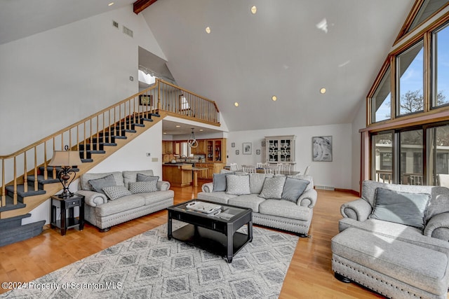 living room with vaulted ceiling with beams and light hardwood / wood-style flooring