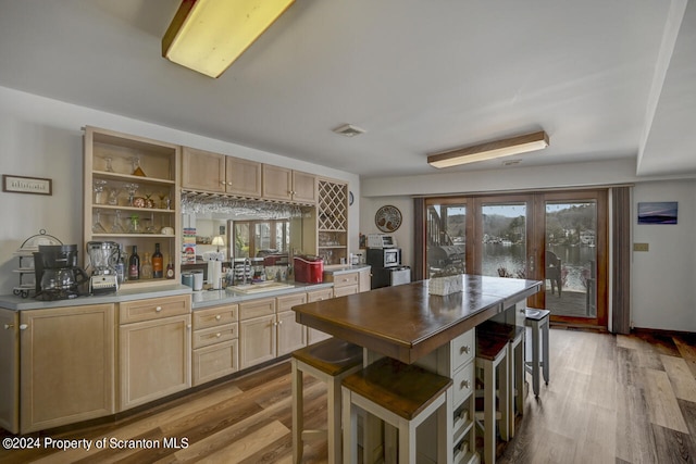 kitchen featuring light brown cabinetry, sink, a breakfast bar, and light hardwood / wood-style flooring