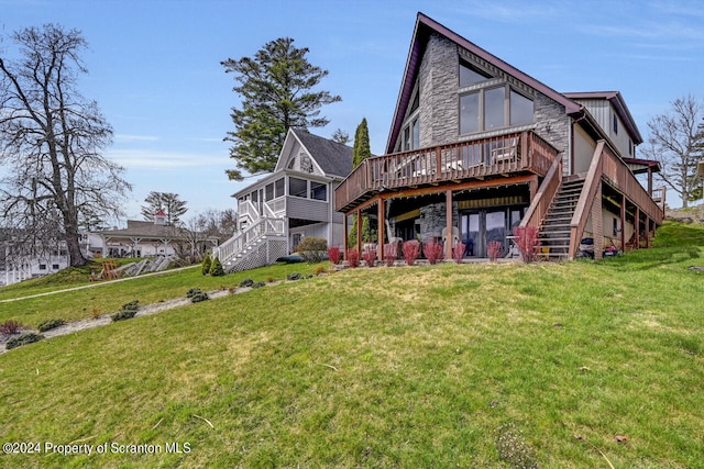 rear view of house with a wooden deck, a sunroom, and a yard