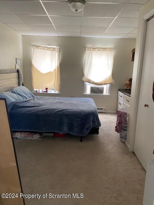 bedroom featuring carpet, a drop ceiling, and baseboard heating