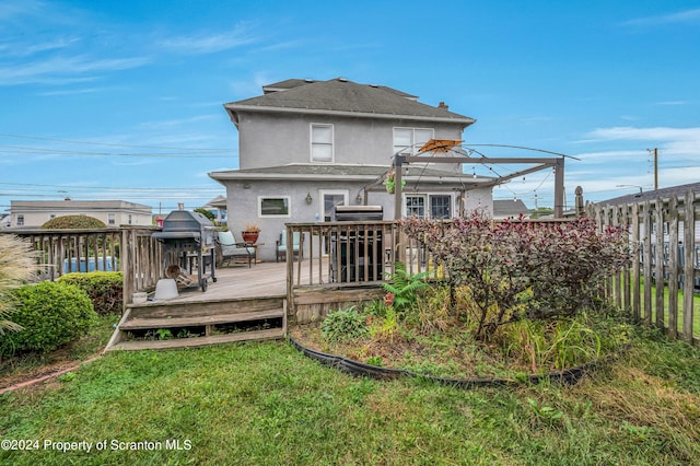 rear view of house with a yard and a wooden deck