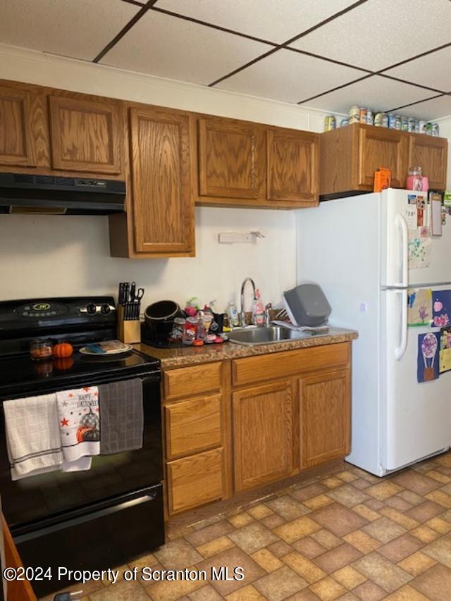 kitchen with a drop ceiling, ornamental molding, sink, white refrigerator, and black / electric stove