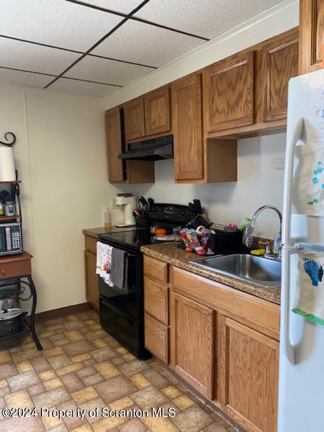 kitchen with a drop ceiling, white refrigerator, sink, ornamental molding, and black range with electric cooktop