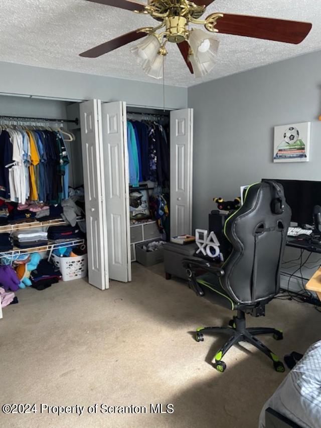 interior space with carpet, a textured ceiling, and ceiling fan