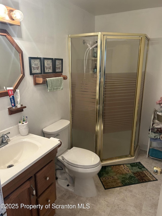 bathroom featuring tile patterned flooring, toilet, an enclosed shower, and vanity