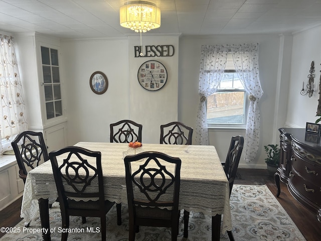 dining area with crown molding and dark wood-type flooring