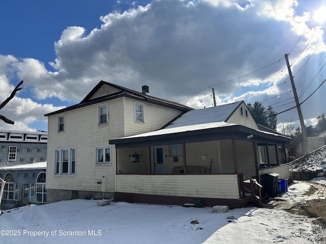 snow covered house featuring a porch