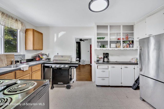 kitchen featuring stainless steel fridge, stove, ceiling fan, sink, and white cabinets