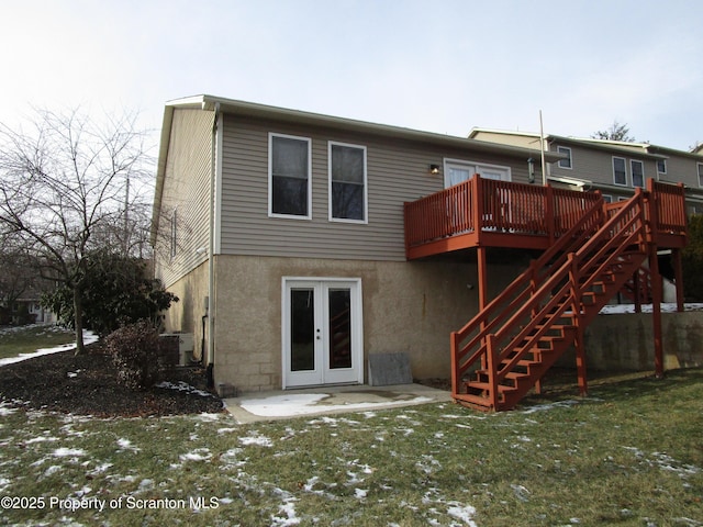 snow covered house with a wooden deck, a yard, and french doors